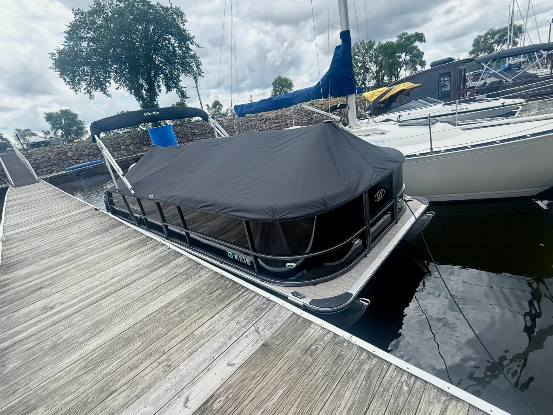 Covered boat docked by wooden pier.