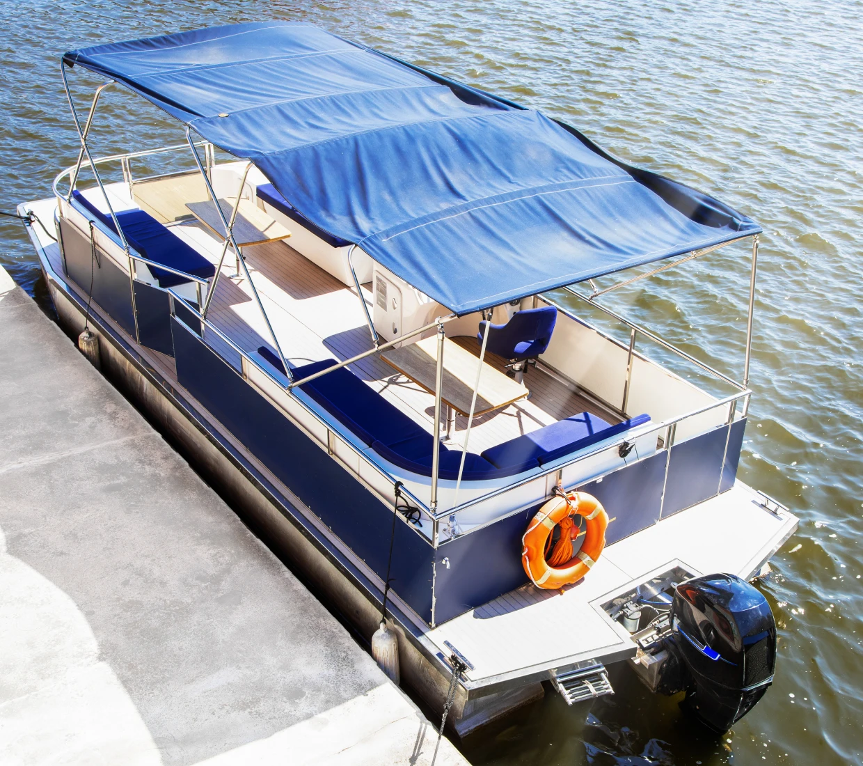 Blue pontoon boat docked by the water
